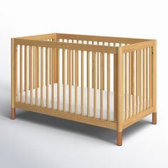 a wooden crib with white sheets on the bottom and sides, in front of a gray background