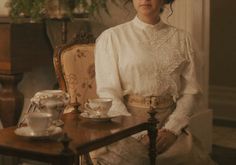 a woman sitting at a table with tea cups