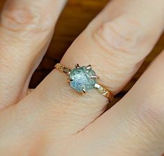 a woman's hand with a ring on it that has a blue stone in the middle