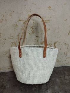 "White sisal tote bag DIMENSIONS Bottom width: 10\"/25.5cm Top width: 14\"/35.56cm Depth: 10\"/25.5cm Straps: 15\"/38cm SHIPPING All orders ship via DHL Express (3-5) days delivery time." Eco-friendly White Bag With Natural Fiber, Eco-friendly White Bag In Natural Fiber, White Tote Bag In Natural Fiber, White Natural Fiber Tote Bag, White Bag With Braided Handles In Natural Fiber, White Bags With Braided Handles In Natural Fiber, White Natural Fiber Bag With Braided Handles, White Natural Fiber Bags With Braided Handles, White Natural Fiber Tote Beach Bag