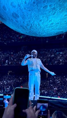 a man standing on top of a stage while holding a cell phone in his hand