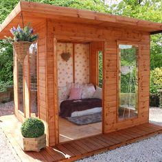 a small wooden cabin with its doors open and a bed in the corner on top of it