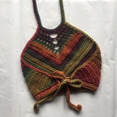 a multicolored crocheted bag tied up on a white sheet with a string