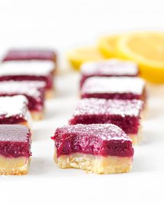 several pieces of cake sitting on top of a white table next to lemons and a slice of orange