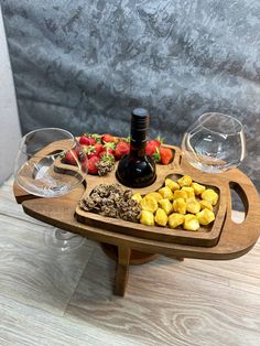 a wooden tray filled with different types of food and wine glasses on top of it