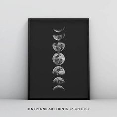 three phases of the moon in black and white on a wall above it is an empty shelf