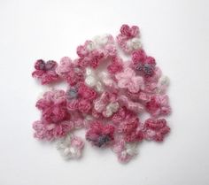 pink and white crocheted flowers on a white surface