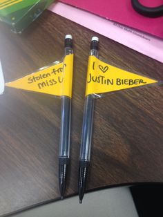 two pens sitting on top of a desk next to each other with writing on them