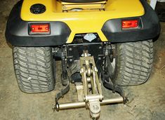 the rear end of a yellow and black four - wheeled vehicle with two large tires