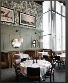 an empty restaurant with tables and chairs in front of large windows that have pictures on the wall