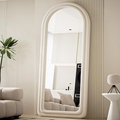 a large white mirror sitting on top of a wooden floor next to a living room