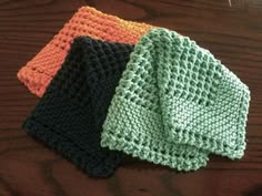 three crocheted dishcloths sitting on top of a wooden table