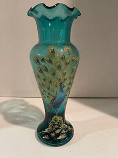 a green vase with a blue peacock on it