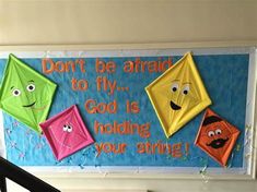 a bulletin board with kites on it that says don't be afraid to fly god is holding your string