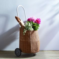 a basket filled with flowers sitting on top of a wooden floor next to a wall