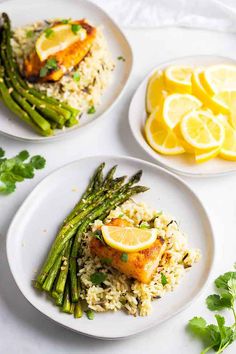 three plates filled with rice and asparagus next to lemon wedges on a white table