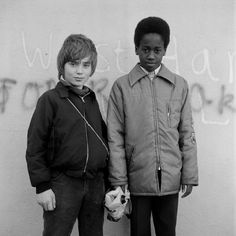 two boys standing next to each other in front of a wall with writing on it