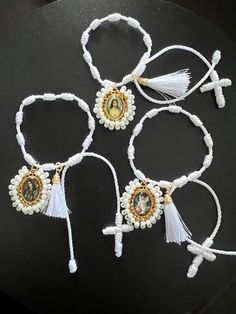 four bracelets with beads and tassels on top of a black table next to each other