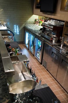 a kitchen filled with lots of stainless steel appliances and counter top covered in wine bottles