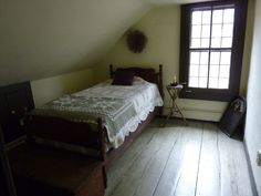 a bed sitting under a window in a bedroom next to a wooden table and chair