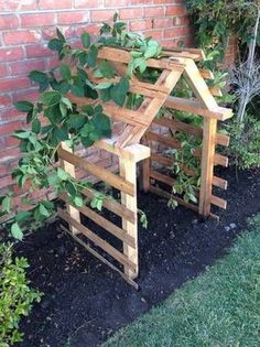 a house made out of wooden pallets sitting next to a brick wall with plants growing in it