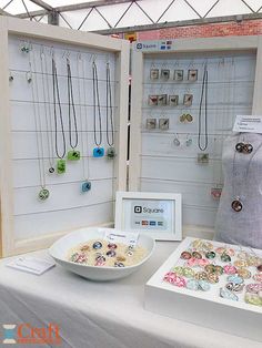 a table topped with lots of necklaces next to a white bowl filled with beads