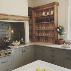 a kitchen with green cabinets and white counter tops, an oven and some fruit on the counter