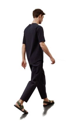 a man walking while wearing slippers and a black t - shirt with no sleeves