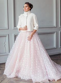 a woman in a white top and pink polka dot tulle skirt standing on a wooden floor