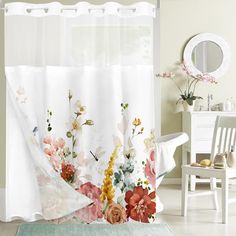 a floral shower curtain hanging on the side of a bath tub in front of a mirror