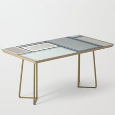 a glass table with metal legs on a white background in front of a gray wall