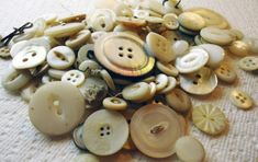 a pile of buttons sitting on top of a white cloth covered floor next to a bottle opener