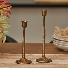 two metal candlesticks sitting on top of a table