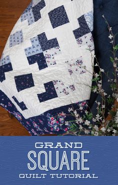 a blue and white quilt sitting on top of a chair next to a vase with flowers