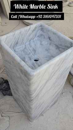 a white marble sink sitting on top of a floor