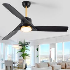 a ceiling fan in a living room with white furniture and large windows overlooking the city