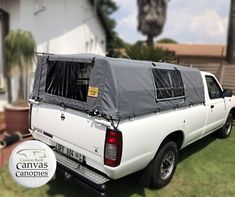 a white pick up truck with a tarp on the back in front of a house