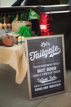 there is a sign that says tailgate and hot dogs on the table next to it