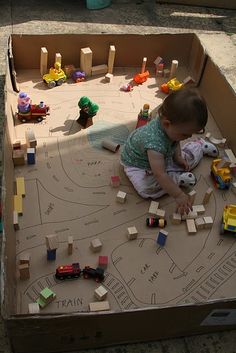 a toddler playing with toys in a cardboard box