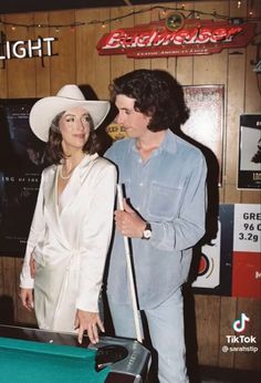 a man standing next to a woman near a pool table