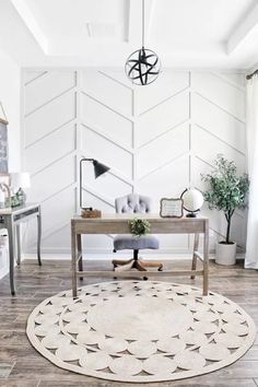 a living room with white walls and wood flooring, a rug on the floor