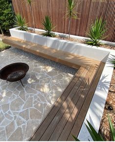 a wooden bench sitting on top of a stone floor next to a planter filled with succulents