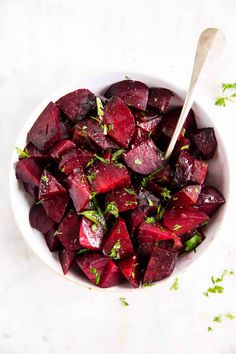 a white bowl filled with cooked beets and parsley