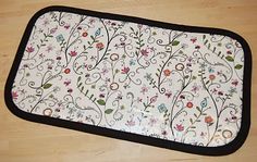 a white and black mat with floral designs on the bottom is sitting on a wooden floor