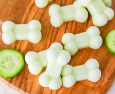 cucumber slices and diced up dog bones on a wooden cutting board with white frosting