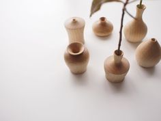 several small wooden vases sitting next to each other on a white counter top with a plant in the middle