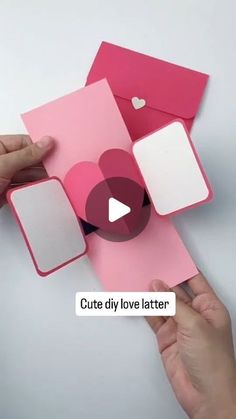 two hands holding pink and white envelopes with heart cutouts on them, while another hand holds out a piece of paper that says cute diy love letter