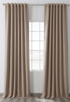 a beige curtain hanging in front of a window with white walls and wooden flooring