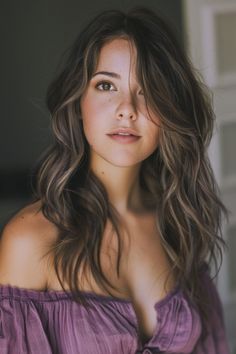 Woman with shoulder-length wavy hair and a purple off-the-shoulder top glancing away thoughtfully. Long Haircuts For Heart Shaped Faces, Old Hollywood Hair