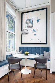 a dining room table with two chairs and a painting on the wall